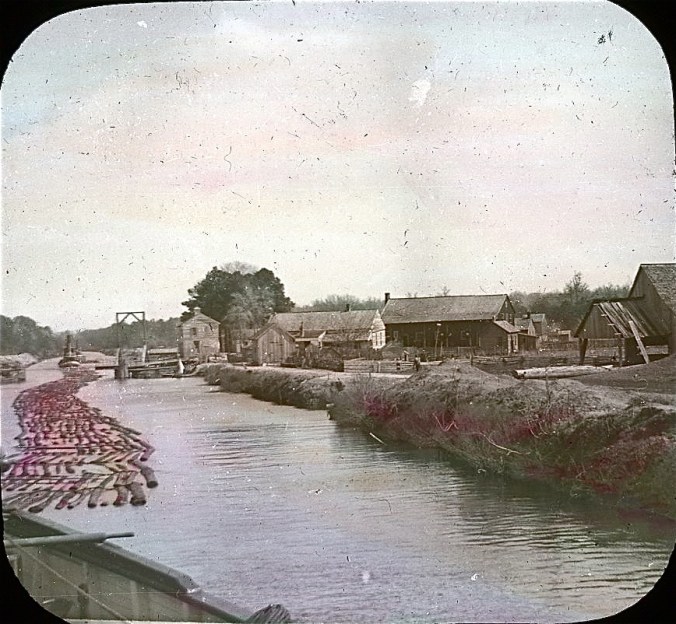 Log raft passing the village of Coinjock, N.C., on the Albemarle & Chesapeake Canal, 1901. Image by Albert Ross, USN. Courtesy, Linda Garey