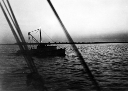 A shrimp trawler at dawn at the mouth of the Cape Fear River, 1938. Even after the Second World War, the classic Carolina shrimp boat was still a 25-foot wooden skiff, local-built, dragging a 15-foot flat-netted, cotton twine otter trawl and powered by a 3-8 horsepower automobile engine.Photo by Charles A. Farrell. Courtesy, State Archives of North Carolina