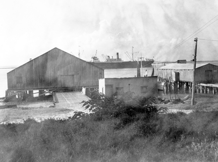 A freighter passes behind a pair of Southport's shrimp houses on the Cape Fear River. Courtesy, State Archives of North Carolina