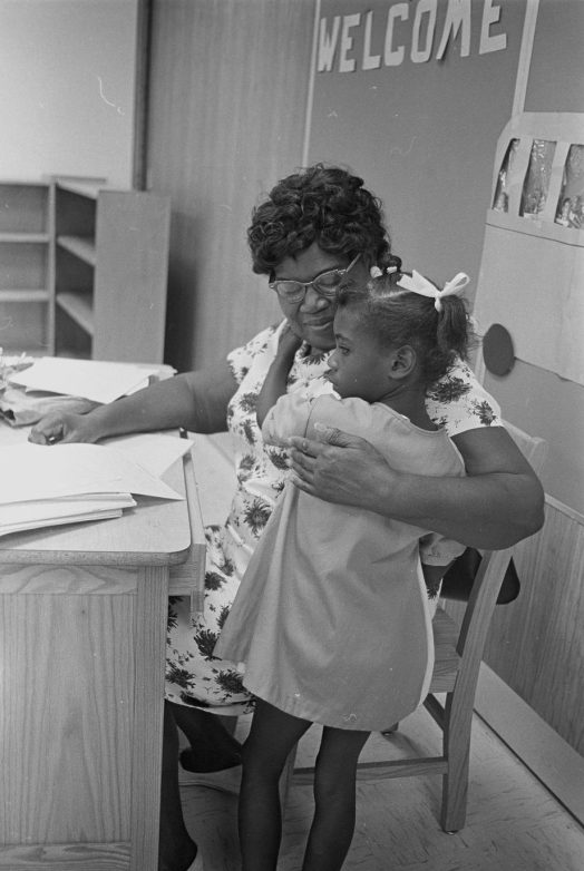 A teacher comforting a child on her first day of school, August 1967. Courtesy, Joyner Library, ECU
