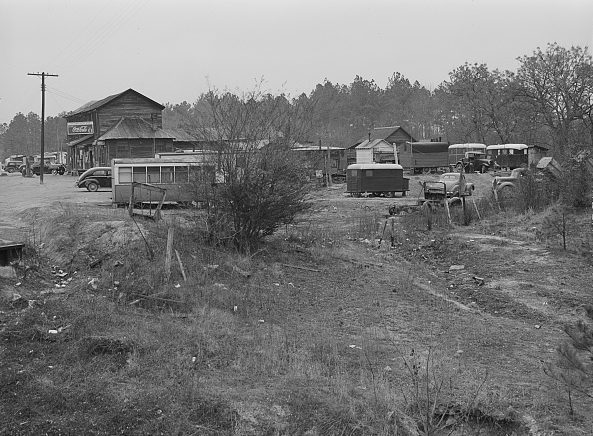 A migrant camp of Ft. Bragg construction workers next to a general store in Manchester, N.C, 12 miles from Fayetteville, Mar. 1941. The workers and sometimes their families lived largely in little trailers, trucks, tiny bunkhouses & even an old trolley car. Photo by Jack Delano. Courtesy, Library of Congress