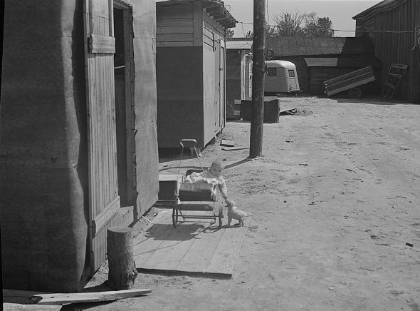 A baby in its stroller in a settlement of shacks built to house Fort Bragg construction workers, near Manchester, 1941. Photo by Jack Delano. Courtesy, Library of Congress