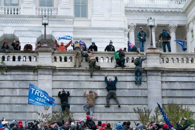 Supporters of Pres. Trump climb the wall on the West Wing of the U.S. Capitol after overrunning police barricades. Photo by Jose Luis Magana, AP.