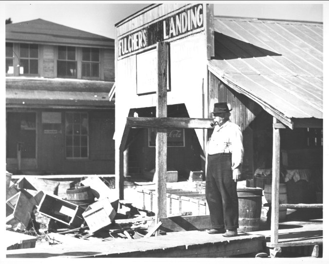 Jim Fulcher at his fish house. His granddaughter, Rosetta Ward, remembered him when she was a very little girl. She said they called him "Old Man Fulcher" or "the patriarch of Fulcher's Landing." She recalled how he settled his accounts with the local fishermen on Friday nights and had a "camp house" behind the store, where duck hunters would stay. Her mother and her sisters would clean the ducks and cook them, while the boys did chores like bringing wood for the stove. He lived in a big house on a hill, had 5 children and had the only telephone in the village. She told me that she remembered the feeling of his mustache when she used to hug and kiss him. Photo by Charles A. Farrell. Courtesy, State Archives of North Carolina