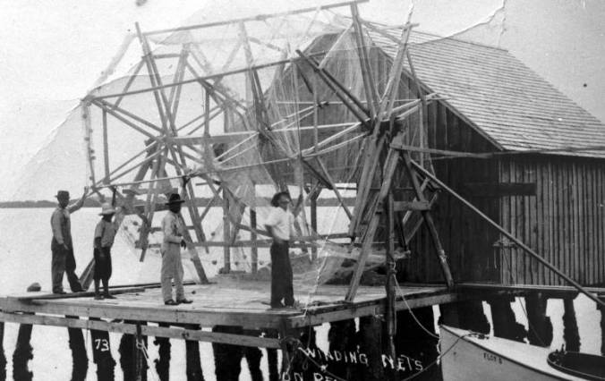 Fishermen and net reel, Cortez, Florida, 1920. Burns, Julian and John Taylor (the three figures on the left)) were all from Carteret County, N.C. John Taylor first homestead on Longboat Key, then came to Cortez. Julian is remembered for his leadership in starting the Cortez Volunteer Fire Department. Courtesy, Manatee County Public Library