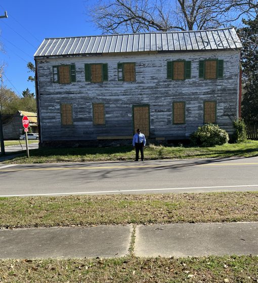 James standing in front of the home and "Green Book" hotel previously owned by Glady Pettiford. Built in 1814, the house was purchased by Ms. Pettiford's father, an African American blacksmith named Reuben Pettiford, a century later, in 1914. 