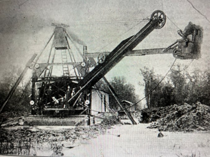 In 1913, Samuel Wilmer, a correspondent for the <em>Manufacturers Record</em> in Baltimore, visited one of John A. and Samuel Wilkinson's drainage projects in the East Dismal Swamp. The Wilkinson brothers had bought a 25,000-acre tract of heavily logged swampland from the Roper Lumber Co. to convert it into farmland. Wilmer wrote: "<em>Back in the woods . . . is a big steam dredge built by the American Steam Dredge Co., Fort Wayne, Ind., working night and day.... It is operated by two crews, one of whom sleeps in a houseboat attached while the other works."</em> The Wilkinsons' two dredges dug somewhere between 150 and 200 miles of canals through the section of the East Dismal between Pinetown and the Pungo River. Their dredging crews dug the main canals 20 feet across and 8 feet deep and located them a mile apart. Since that time, the drainage of those freshwater wetlands primarily into the Pungo River has had a profound effect on the Pamlico Sound estuary and its commercial fisheries.  Photo from Samuel G. Wilmer, "New Railroad and Drainage Work," <em>Manufacturers Record</em> (Baltimore, Md.), 1 Jan. 1914