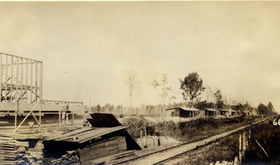 This is a remote labor camp called Wonderland, on the border of Washington County and Beaufort County, N.C., November 1917. The railroad tracks are those of the Norfolk &amp; Southern. On the left, we can see a company store and post office being built. On the right, we can see barracks for black workers that were logging, clearing, and burning and re-burning what was left of the East Dismal Swamp. After logging the swamp forest, the Roper Lumber Co. had sold 40,000 acres of their holdings in the East Dismal to Mark W. Potter, a wealthy New York attorney who was president of the Ohio, Clinchfield &amp; Carolina Railway Co. (a subsidiary of the Norfolk &amp; Southern). Going into business with John A. and Samuel Wilkinson, Potter aimed to reclaim the logged swamplands, subdivide the land, and sell plots to farmers recruited mainly in the Midwestern states. According to federal records, Wonderland only had a post office from 1917 to 1925. Once the ground was made ready for farming, the little settlement disappeared and was soon forgotten. Other land developers attempted similar plans on the Roper Lumber Co.'s former holdings. Most, including the Wilkinson brothers, ended up making little if any profit from them, though by the time they added up their losses only a scattered few thousand acres of the East Dismal was left. From <em>Views of Potter Farms Development: Showing Various Stages in the Evolution of Potter Farms</em> (1917),  North Carolina Collection, Wilson Library, UNC-Chapel Hill
