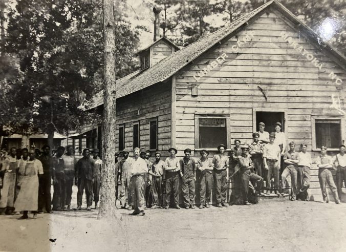 Workers posing at the commissary at the Makatoka logging camp, ca. 1913. The men in white on the left are probably the camp's cooks. From Waccamaw Lumber Co. Photograph Album and Journal, Rubenstein Library, Duke University