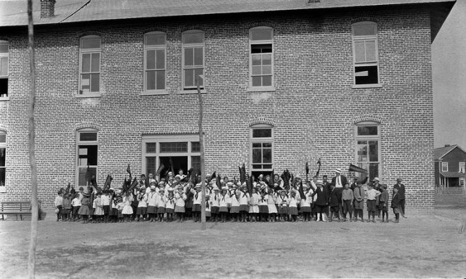 Children holding a banner that says "Pinetown" at a school in Pinetown, N.C., ca. 1910. At that time, all of North Carolina's schools were segregated by race. All of these children are white, but I do not know if there was also a school for black children nearby. In fact,I do not know if Surry Parker employed African Americans or permitted them to reside in Pinetown. I have never seen African Americans in photographs of Pinetown. Courtesy, Surry Parker Photograph Collection, State Archives of North Carolina