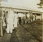 Neil Howell, who grew up near Kinston, N.C., was 17 years old when he enrolled in CCC Co. 424. At a reunion in 1993, he remembered his first days in Hyde County. "I was scared," he told an AP reporter. "I had never been away from home before." Howell soon got over his homesickness though. "We had a good bunch of people," he remembered. Quote is from the the <em>Greensboro News &amp; Record</em>, 7 June 1993. In this photo, we can see the camp's enrollees lining up outside the mess hall at Bell Island. Photo courtesy, State Archives of North Carolina