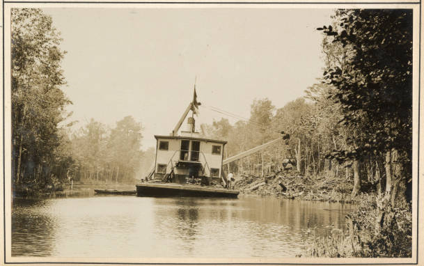 Stern view of derrick barge No. 14 on the Scuppernong River, May 1931. According to the Corps' annual report, the barge's crew removed 22,152 cubic yards of earth, roots, and stumps in and along the banks of the Scuppernong that spring. Source: Office of History, HQ, U.S. Army Corps of Engineers