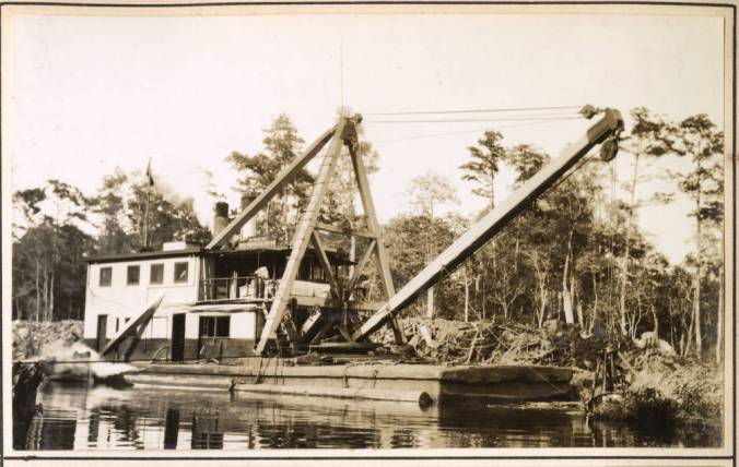 The Corps' derrick barge <em>No. 14 </em>on Turners Cut, September 1931. Originally dug in 1856, Turners Cut is a canal that runs 4 miles from the south end of the Dismal Swamp Canal in South Mills, N.C., to the Pasquotank River, 12 miles north of Elizabeth City. Two years earlier, in 1929, both Turners Cut and the Dismal Swamp Canal had become part of the Intracoastal Waterway (IWW), the network of natural waterways and canals that provided an inland passage for maritime traffic at that time from the Delaware River to Beaufort, N.C. (In 1931 the Corps was in the process of extending the IWW to Wilmington, N.C.) In this photograph, the <em>No. 14's</em> crew is removing a shoal that began just below the canal lock at South Mills and extended 2,500 feet into Turners Cut, a project that took several months in both 1930 and '31. Source: Office of History, HQ, U.S. Army Corps of Engineers