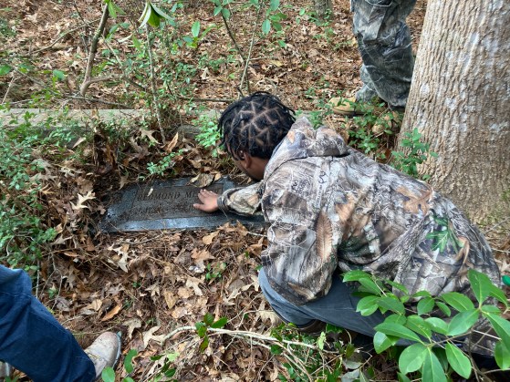 BJ Herring clearing leaves and debris off a grave marker near Pinch Gut Creek. Photo by David Cecelski