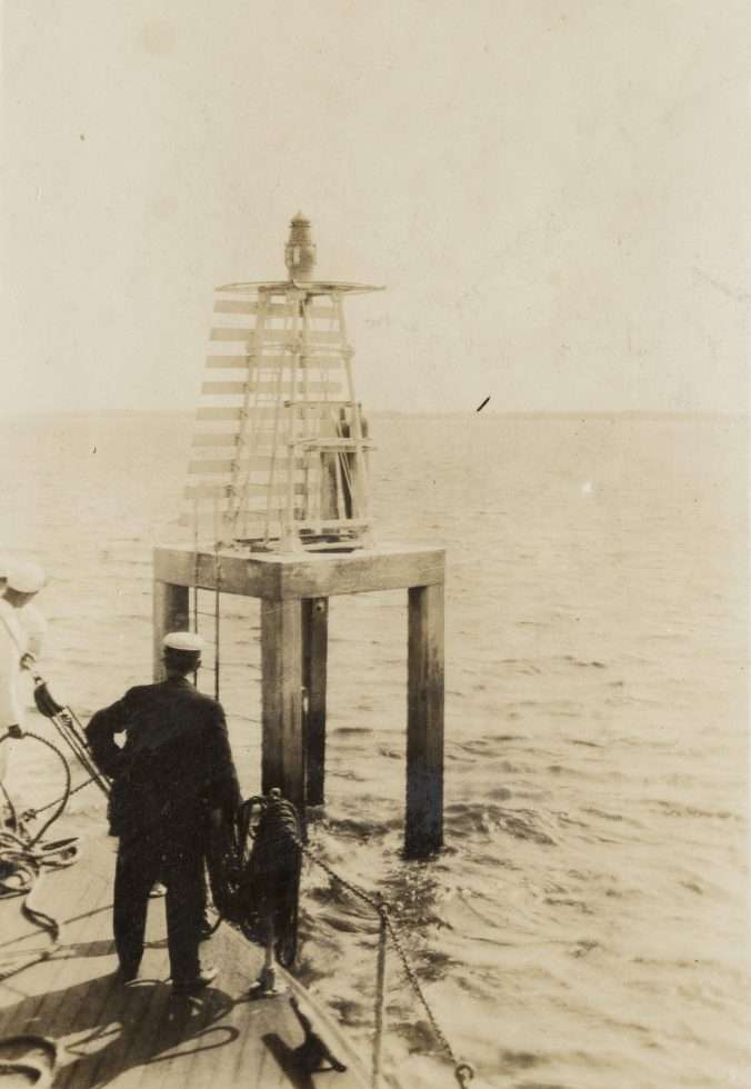 In this photograph, we see the U.S. Lighthouse Service tender <em>Palmetto</em> approaching the range light that marked Upper Midnight Channel on the Cape Fear River between Southport and Wilmington, May 1917. USLS Keeper Berry, in the foreground, was responsible for the maintenance of a series of post lights on the Cape Fear stretching 14 miles from Upper Liliput Channel all the way to the Atlantic. Source: Records of the U.S. Coast Guard (RG 26), National Archives-College Park (#45697828)