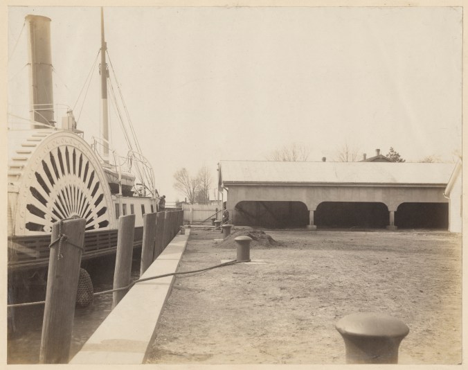 Another view of what I believe is the USLS paddlewheel tender <em>Jessamine</em> tied up at the buoy depot in Washington, N.C., March 1914. Built at the <a href="https://www.thebmi.org/bethlehem-steel-legacy-project/bethlehem-baltimore-shipyards/">Malster &amp; Reaney shipyard</a> in Baltimore in 1881, the <em>Jessamine</em> was based at the 5th Lighthouse District's headquarters in Baltimore but her crew built and maintained lighthouses and tended buoys and other navigational aides across much of the North Carolina coast. Like all USLS tenders, she was a tough, seaworthy vessel, constructed with a hull, deck framing, and the rest of her superstructure having "a large reserve of strength," to quote a <a href="https://uslhs.org/sites/default/files/attached-files/US%20Lighthouse%20Service%201915.pdf">1915 USLS repor</a>t. Lighthouse tenders had to be capable of handling violent storms on the open ocean, as well as to navigate along shoals where shallow draft and a solid hull, capable of putting up with accidental groundings, was required. Note the <em>Jessamine's</em> forward mast, which doubled as a derrick for construction work and for hoisting and lowering buoys. The <em>Jessamine</em> was not, by the way, the only USLS tender with a botanical name. Since 1867, the USLS had named its lighthouse tenders after trees, flowers, or other plants, generally one native to the area where a tender operated. Source: Records of the U.S. Coast Guard (RG 26), National Archives- College Park (#<span class="display-block width-full">45694879)</span>
