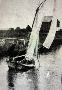 A sail skiff on Mashoes Creek, with a net reel and a fish camp built on pilings in the background, 1939. Greensboro News & Record (19 Nov. 1939)