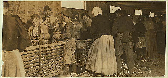 Oyster shuckers in Dunbar, Louisiana, March 1911. The gentleman with the pipe is the padrone who recruited them in Baltimore. Photo by Lewis Hine. Source: National Child Labor Committee Collection, Library of Congress, Division of Prints and Photographs