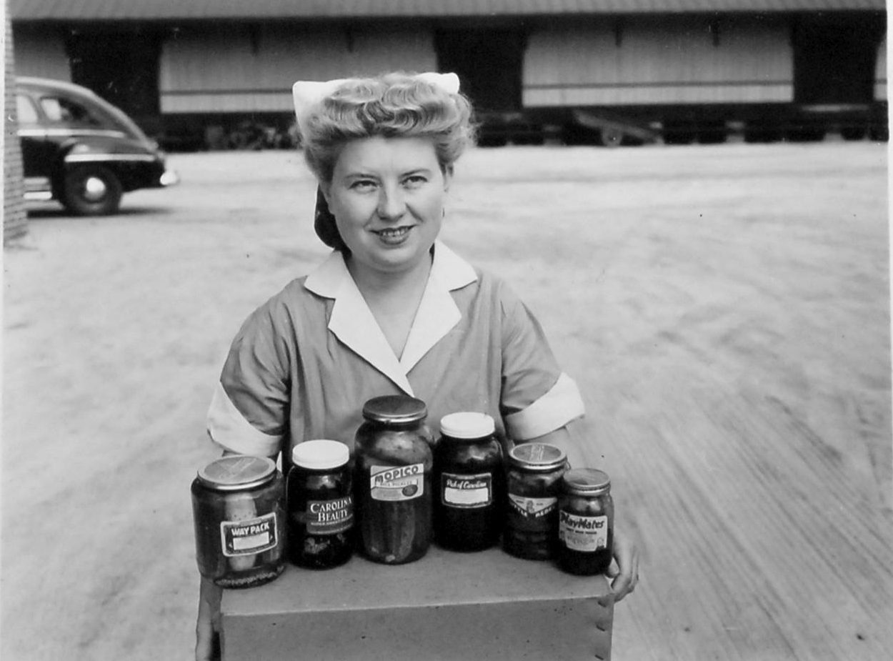 A young woman displaying samples of different brands of pickles that the Mount Olive Pickle Co. marketed in 1947. Courtesy, State Archives of North Carolina