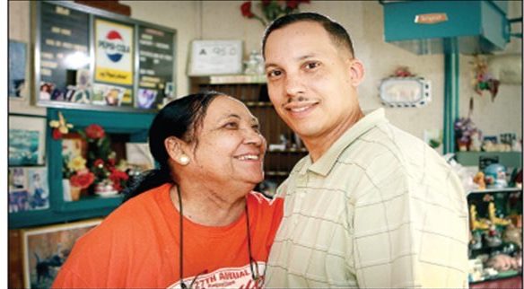 John's mother Yvonne Parker smiles up at him at the restaurant back in 2012. By that time, John had moved away from Goldsboro but he was still in charge of marketing the family's barbecue sauce across the country. Photo courtesy, 27 May 2012. 
